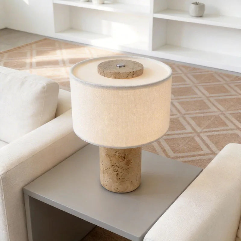 Siena cordless travertine lamp with a fabric drum shade by a sofa