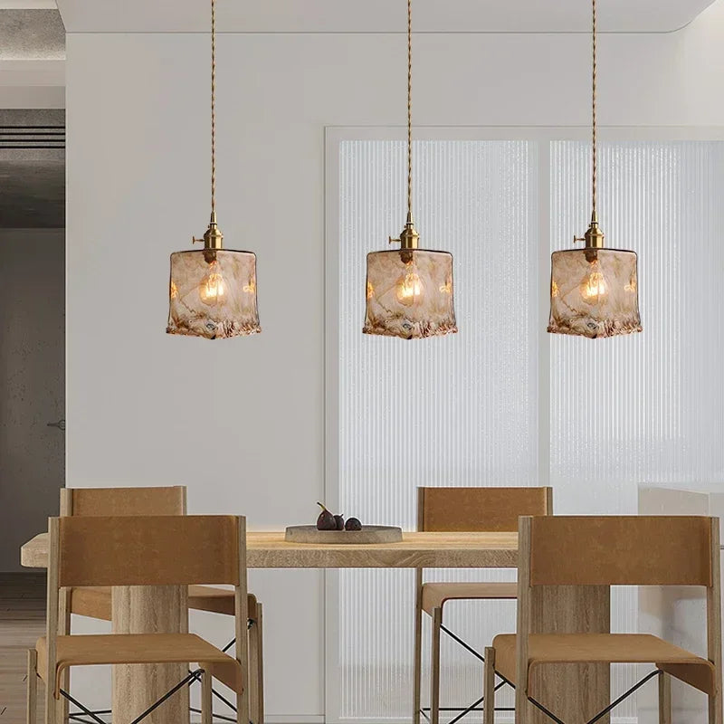Three Aurelia amber glass pendants hanging above a dining table
