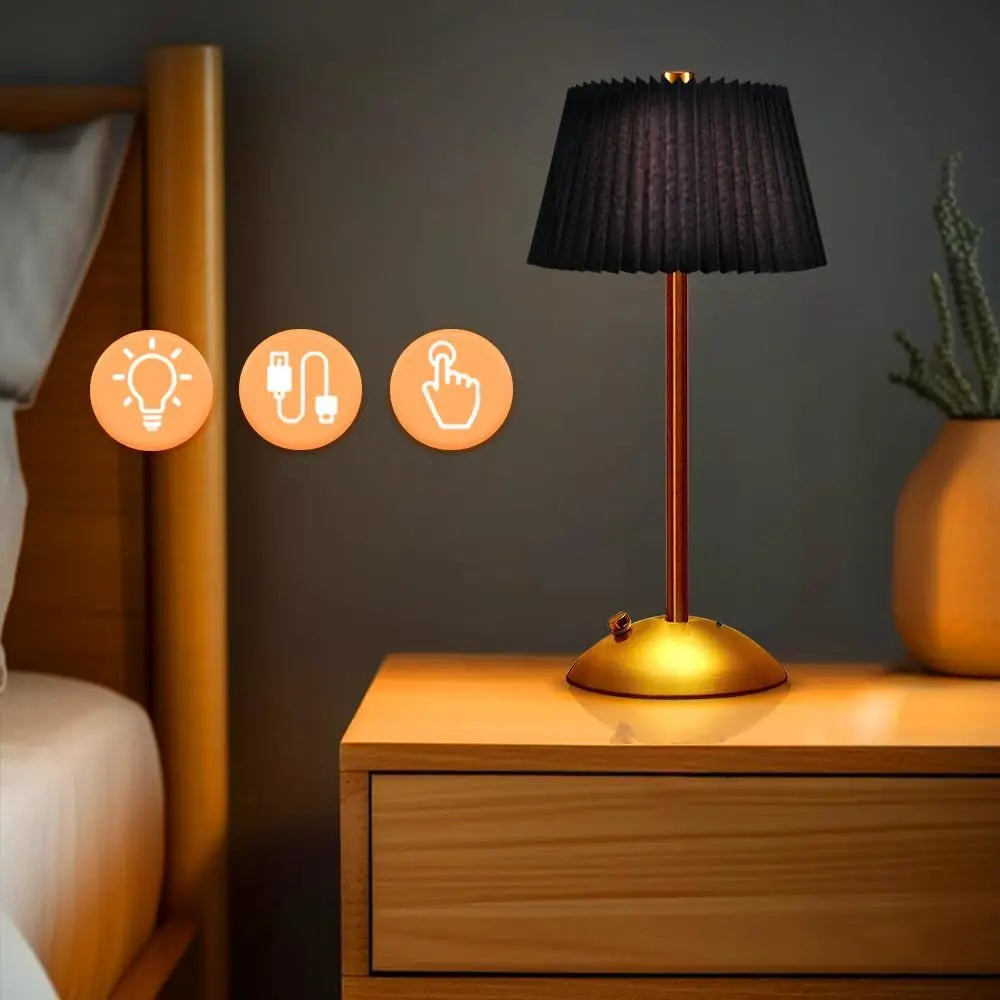 Black Elara cordless pleated lamp glowing on a bedside table