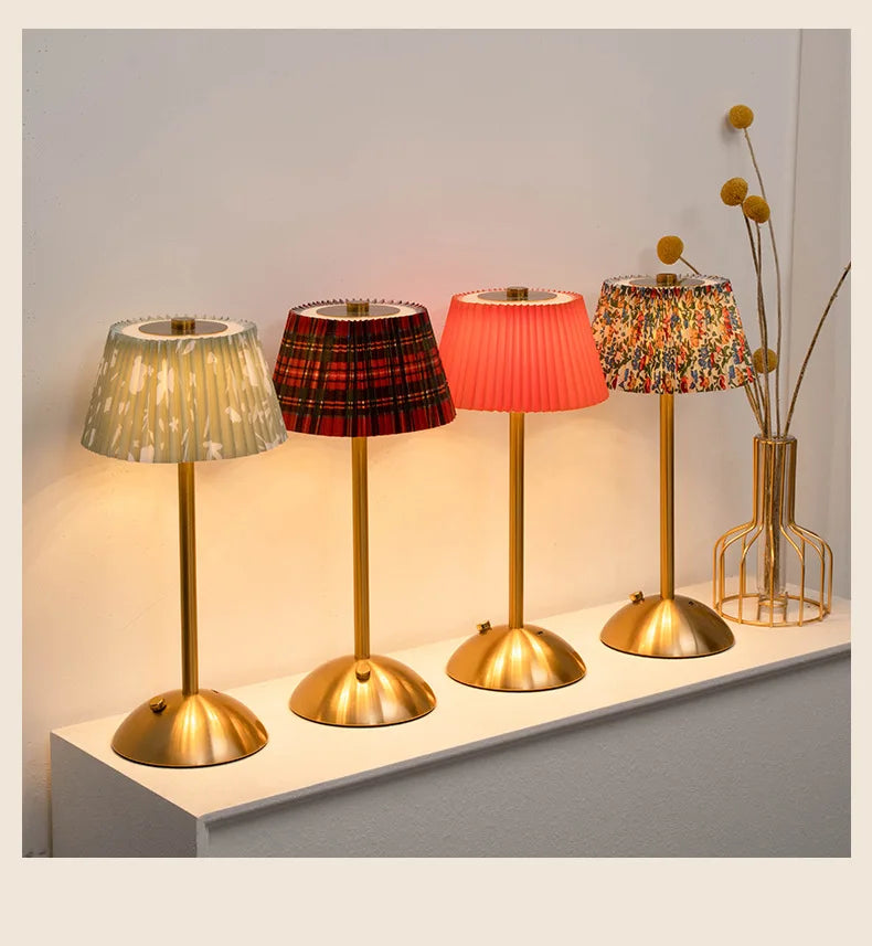 Four Elara cordless pleated lamps displayed together on a white shelf