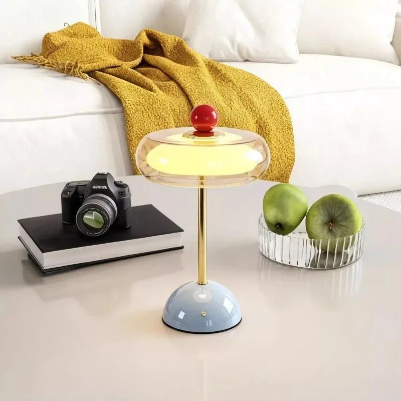 Blue Sorrel cordless glass lamp beside a camera and green apples