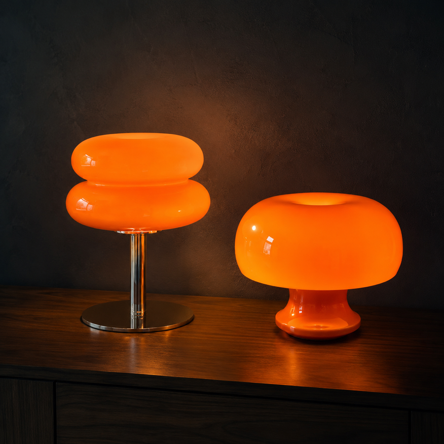 The Amber Pair: Ambra amber glass dome lamp and Oslo orange acrylic dome lamp lit together on a walnut console