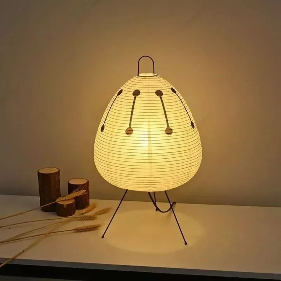 Ember Sora printed paper lantern lamp on steel tripod legs, lit on a pale surface