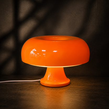 Orange Oslo mushroom table lamp glowing against a dark backdrop